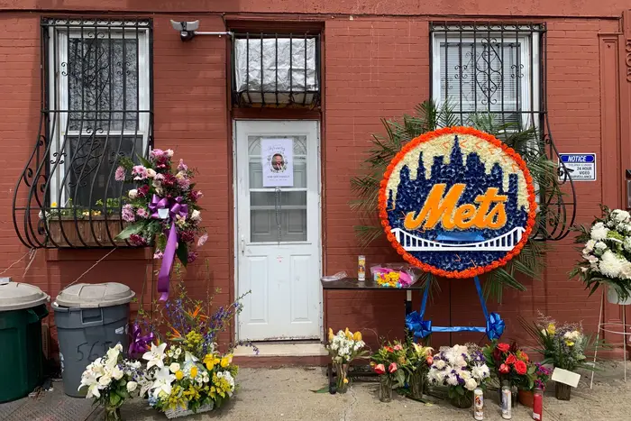 A memorial for the late Jose "Joe" Padilla outside a Brooklyn apartment consisting of flowers and a Mets wreath.